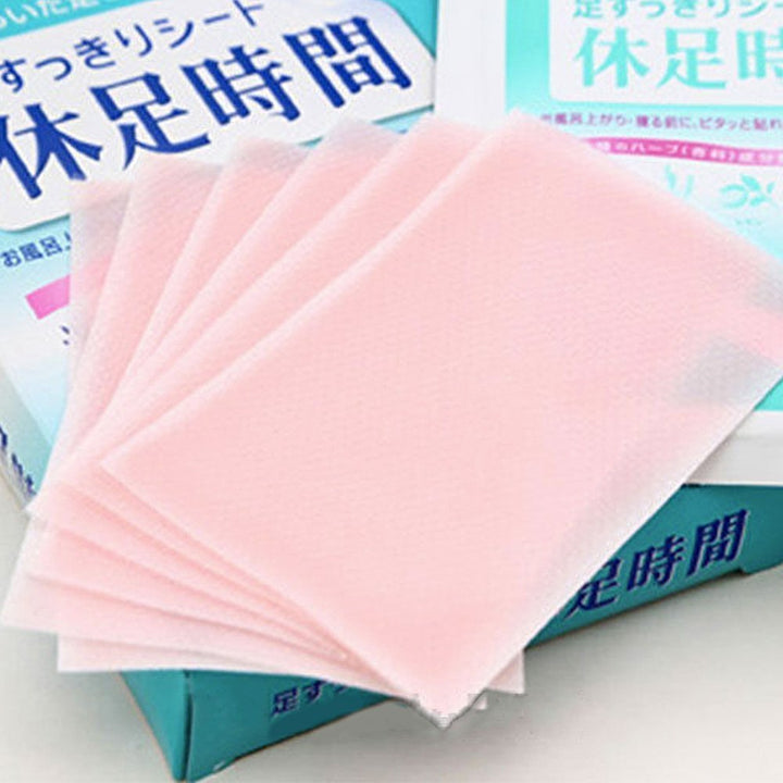 A fan of translucent pink adhesive foot wraps placed over teal and white Japanese product packaging.